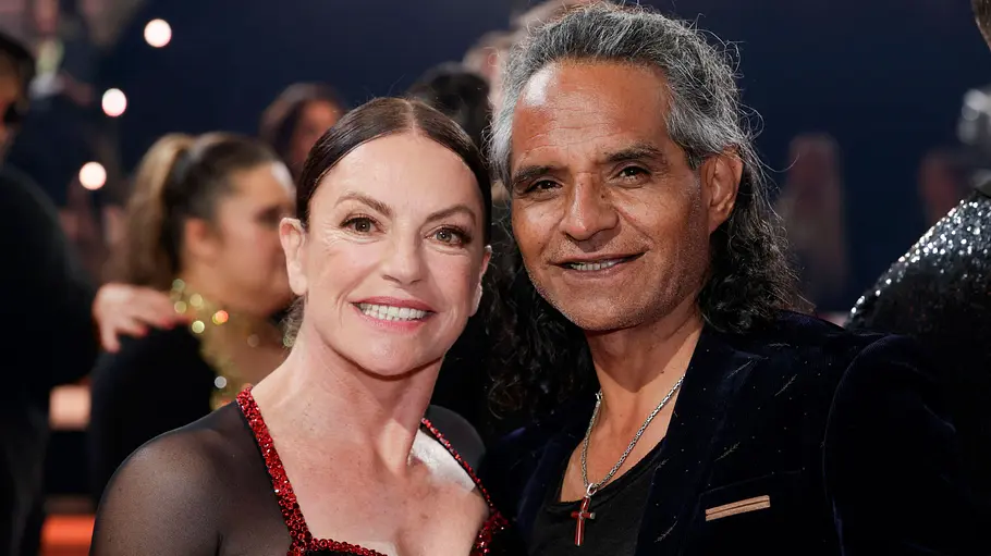 Christine Neubauer und Mann José Campos Hochzeit Shitstorm Kleid. Christine Neubauer im schwarz-roten Kleid und Ehemann José Campos mit langen grauen Haaren und dunklem Sakko lächeln gemeinsam in die Kamera.