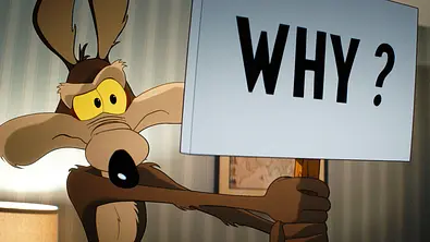 Wille E. Coyote hält ein Schild mit der Aufschrift „Why“ hoch. - Foto: © 2026 Warner Bros. Entertainment Inc. Wille E. Coyote hält ein Schild mit der Aufschrift „Why“ hoch. - Foto: © 2026 Warner Bros. Entertainment Inc.