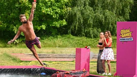 Ein Kandidat wagt sich in das Abenteuer und springt hoch hinaus: In ein Becken voller Wasser. Gespannt stehen Fieldreporterin Julia Römmelt und Teampartnerin am Spielfeldrand.  - Foto: Joyn / Willi Weber