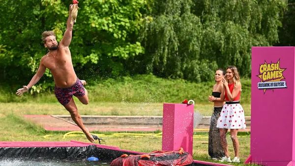 Ein Kandidat wagt sich in das Abenteuer und springt hoch hinaus: In ein Becken voller Wasser. Gespannt stehen Fieldreporterin Julia Römmelt und Teampartnerin am Spielfeldrand.  - Foto: Joyn / Willi Weber