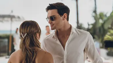 Nick mit Sonnenbrille und Hemd schaut Noah an, die mit dem Rücken zu sehen ist. - Foto: Prime Video
