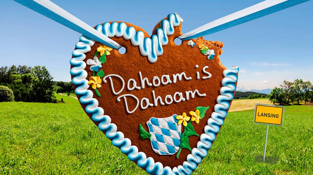 Wird Dahoam abgesetzt? Der „Dahoam is Dahoam“-Schriftzug auf einem Lebkuchenherz baumelt vor ländlicher Kulisse.