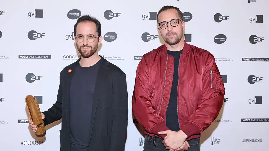 Igor Levit und Danger Dan Igor Levit und Danger Dan stehen mit einem Preis vor einer Fotowand.