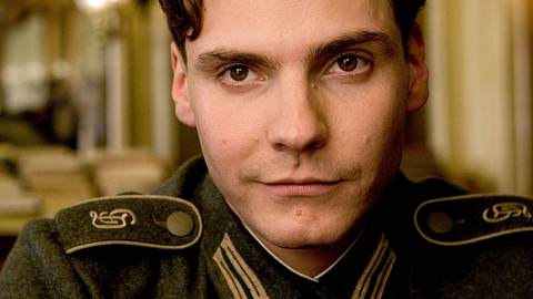 Daniel Brühl schaut bei einem Film in die Kamera und hat eine alte Uniform an - Foto: IMAGO / Everett Collection