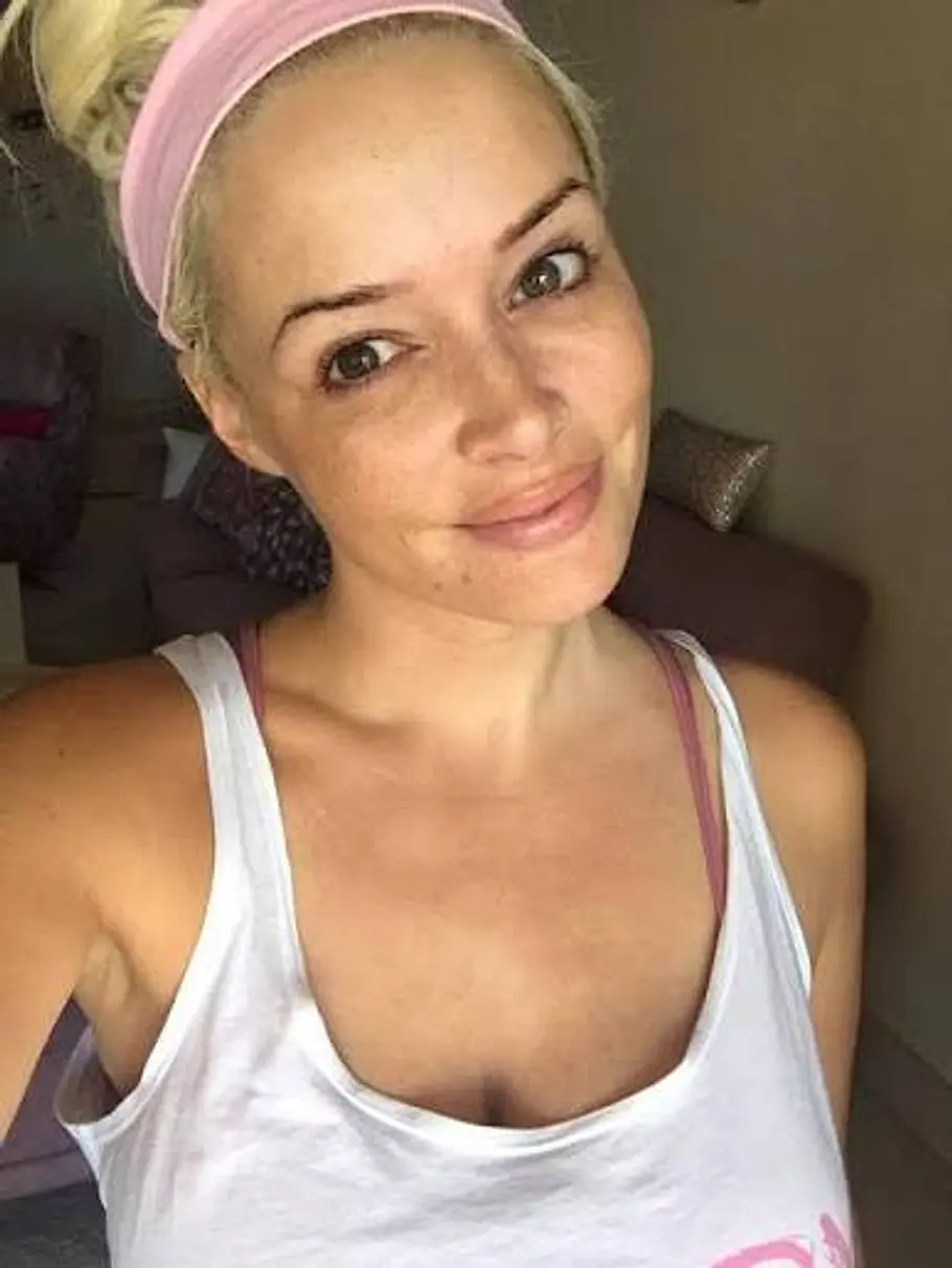 Daniela Katzenberger ungeschminkt Daniela Katzenberger trägt ein rosa Stirnband und ein weißes Trägertop. Mit hochgebundenen Haaren lächelt sie ungeschminkt in die Kamera.