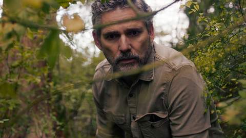 Eric Bana als Kyle Turner. Er schaut Besorgt durch die Äste eines dicht bewachsenen Waldes. - Foto: Netflix