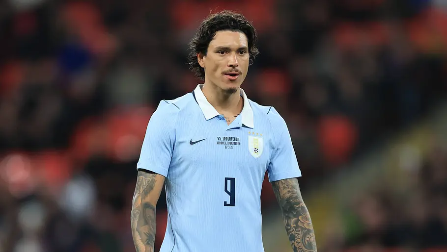 Ein Fußballspieler der uruguayischen Nationalmannschaft steht im hellblauen Trikot mit der Rückennummer 9 konzentriert auf dem Spielfeld. Im Hintergrund ist das Stadion unscharf zu erkennen.