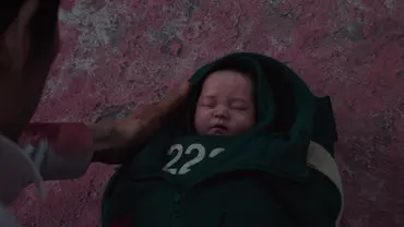 Gi-hun hält ein Baby in den Händen, das in zwei Jacken eingewickelt wurde. - Foto: Netflix Gi-hun hält ein Baby in den Händen, das in zwei Jacken eingewickelt wurde. - Foto: Netflix
