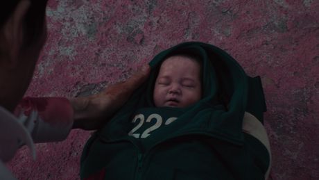Gi-hun hält ein Baby in den Händen, das in zwei Jacken eingewickelt wurde. - Foto: Netflix
