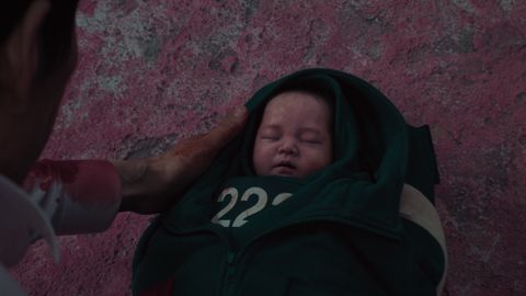 Gi-hun hält ein Baby in den Händen, das in zwei Jacken eingewickelt wurde. - Foto: Netflix