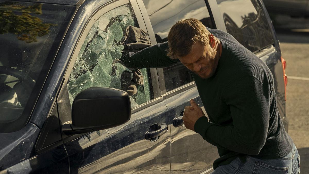 Das gefällt nicht mal Jack Reacher: Prime Video zeigt immer mehr Werbung! Jack Reacher schlägt mit der rechten Faust die Scheibe eines Autos ein.