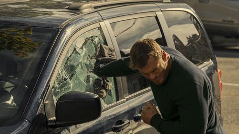 Jack Reacher schlägt mit der rechten Faust die Scheibe eines Autos ein. - Foto: Prime Video