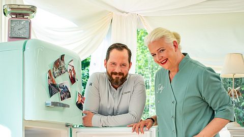 Christian Hümbs und Bettina Schliephake-Burchardt posieren lächelnd neben einem Kühlschrank für die Kamera - Foto: SAT.1