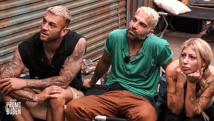 Serkan, Rafi und Bellydah Serkan, Rafi und Bellydah sitzen beim Promi Büßen auf einem Feldbett und lauschen einer Runde der Schande