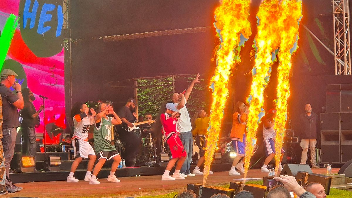 Das Publikum in der ersten Reihe war dankbar über die Möglichkeit, die nasse Kleidung an den Feuerfontänen zu trocknen. Will Smith mit seinen Tänzerinnen auf der Bühne, vor ihnen schießen drei Feuersäulen in die Luft.