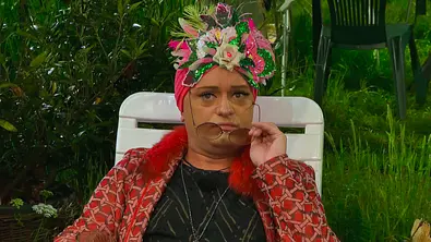 Julian F.M. Stöckel sitzt auf einem weißen Stuhl, trägt einen blumigen Turban, zieht sich seine Sonnenbrille vom Gesicht und schaut irritiert. - Foto: RTL Julian F.M. Stöckel sitzt auf einem weißen Stuhl, trägt einen blumigen Turban, zieht sich seine Sonnenbrille vom Gesicht und schaut irritiert. - Foto: RTL