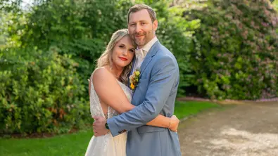 Michelle im weißen Brautkleid und Fabian im hellblauen Anzug umarmen sich vor grünen Büschen in einem Garten. - Foto: Joyn/Christoph Assmann Michelle im weißen Brautkleid und Fabian im hellblauen Anzug umarmen sich vor grünen Büschen in einem Garten. - Foto: Joyn/Christoph Assmann