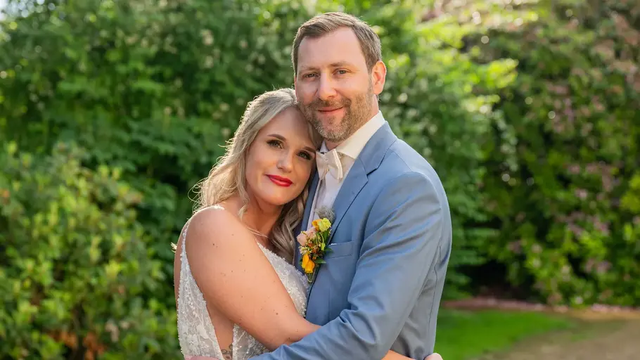 Das TV-Experiemente manchmal auch ein Happy End haben, beweisen Michelle und Fabian. Michelle im weißen Brautkleid und Fabian im hellblauen Anzug umarmen sich vor grünen Büschen in einem Garten.