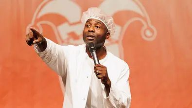 Dave Davis als Motombo Umbokko mit Mikro zeigt nach vorne. - Foto:  IMAGO / Funke Foto Services