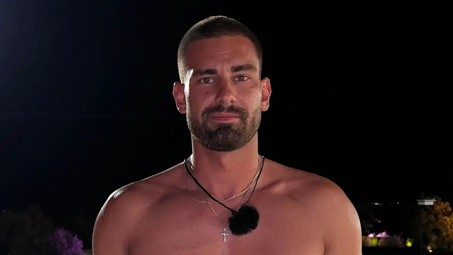 David, 27 Ein bärtiger Mann mit freiem Oberkörper, Halsketten und Mikrofon steht nachts vor einem beleuchteten Pool.