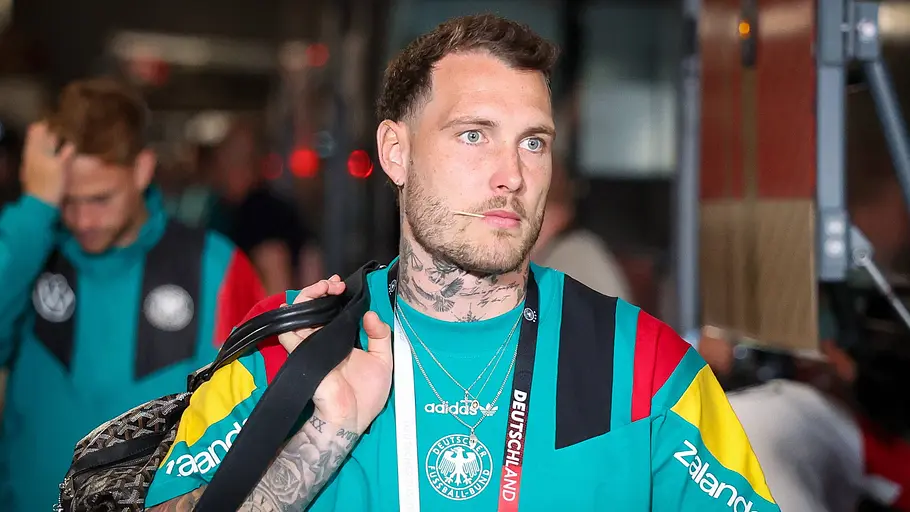 David Raum David Raum geht lässig mit einer Sporttasche einen Gang entlang.