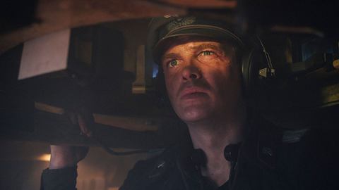 David Schütter in „Der Tiger“: Er sitzt im Panzer und blickt aus der Luke hinaus. Ein Auge zusammengekniffen, das andere wachsam. Auf dem Kopf trägt er große Kopfhörer und einen Helm, gekleidet in eine Wehrmachtsuniform des Zweiten Weltkriegs.  - Foto: Amazon MGM Studios