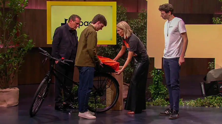 Den Mehrwert von allpacka One konnten alle Löwen erkennen. Löwe Ralf Dümmel, Gründer, Jonathan Vincentz, Löwin Janna Ensthaler und Gründer Lukas Ludwig stehen an einem Fahrrad.