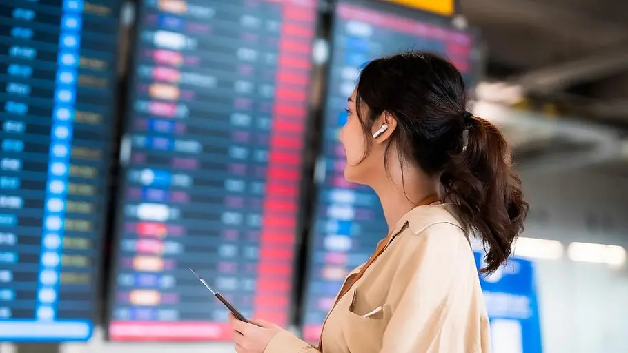 Denon AH-C840NCW Eine Frau am Flughafen mit Noise Canceling Kopfhörern im Ohr