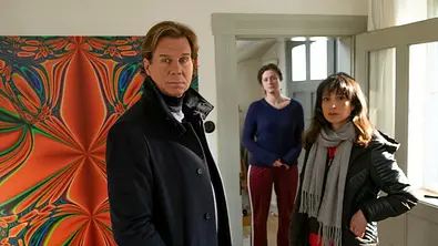 Der Alte – Blaue Stunde: Caspar Bergmann (Thomas Heinze) und Annabell Lorenz (Stephanie Stumph) schauen sich zuhause beim Opfer Ada Sahin um. Ihre Mitbewohnerin Caro Glanz (Rosalie Schlagheck) steht hinter den beiden im Türrahmen. - Foto:  ZDF/Erika Hauri