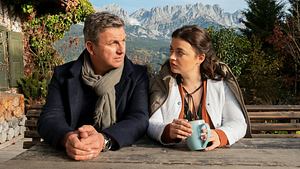 Der Bergdoktor und eine Frau sitzen draußen an einem Tisch. - Foto: SRF/ZDF/Erika Hauri