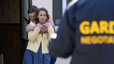Ronan hat einen Arm und seine noch Ehefrau Grace geschlungen und hält eine Pistole in der anderen. - Foto: ARD