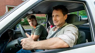 Stefan Vollmer sitzt im Auto neben seinem Schüler im Auto und lächelt - Foto: RTL / Steffen Junghans