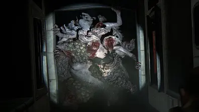Eine aus mehreren Zombies bestehende Kreatur bricht durch eine Tür und wird von einer Taschenlampe beleuchtet. - Foto: Naughty Dog