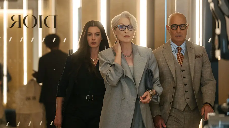Andy, Miranda und Nigel in Der Teufel trägt Prada 2 Miranda Priestly schreitet selbstbewusst durch einen eleganten Dior-Store, begleitet von Andy und Nigel, während Kameras auf sie gerichtet sind.