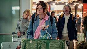 Jess mit Koffern und Hund am Flughafen. Sie schaut skeptisch zur Seite. - Foto: © 2024 Netflix, Inc.