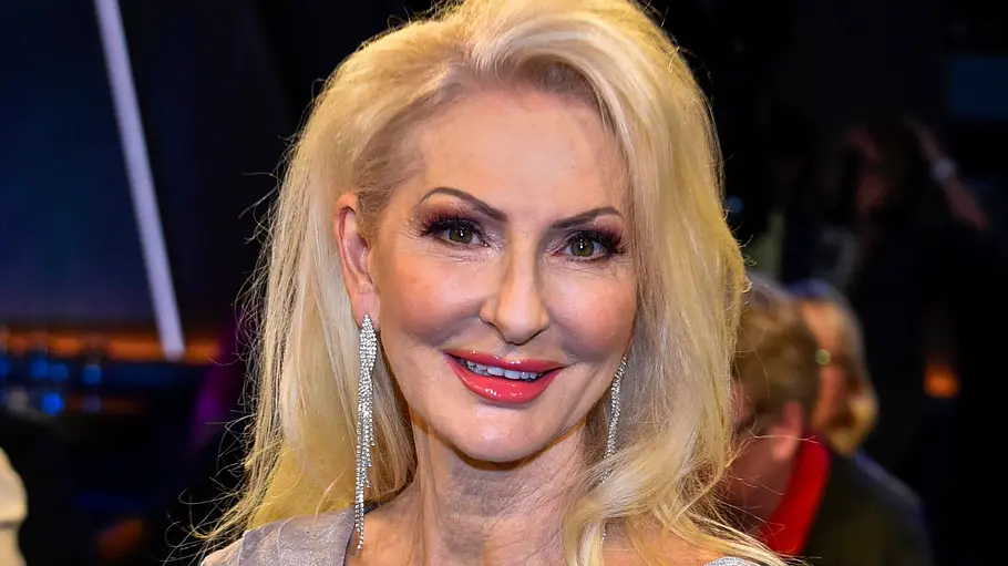 Désirée Nick im TV-Studio Désirée Nick sitzt in einem TV-Studio auf einem Sessel, trägt ein glänzendes Kleid und lächelt in die Kamera