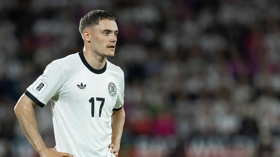 Florian Wirtz steht auf dem Feld und packt seine Hände auf seine Hüften.