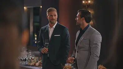 Sebastian und Tim im Anzug stehen bei einem Empfang nebeneinander, halten jeweils ein Glas in der Hand und unterhalten sich. - Foto: RTL