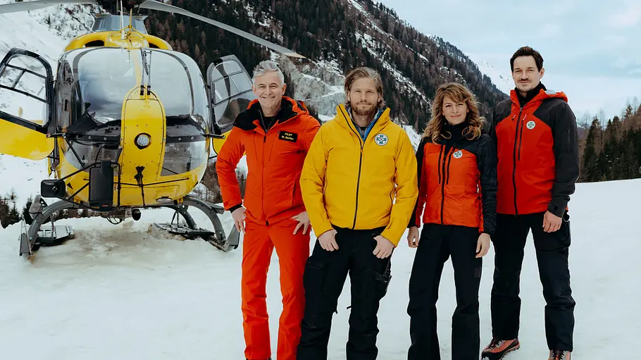 Die Bergretter Markus Kofler steht mit drei weiteren Mitgliedern seines Teams vor einem Hubschrauber in den Bergen.