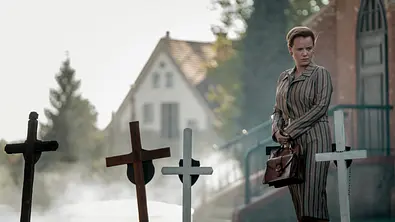 Eine Frau steht auf dem Friedhof einer Kirche. - Foto: Robert Pałka / Netflix