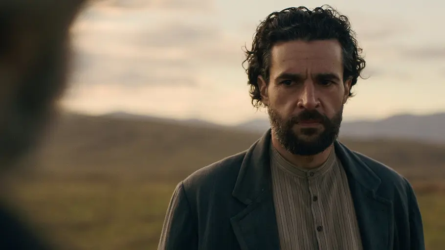 Die Familie Trask entsammt John Steinbecks Fantasie. Christopher Abbott als Adam Trask steht mit Bart und dunklem Mantel vor einer kargen Landschaft und blickt ernst nach links.