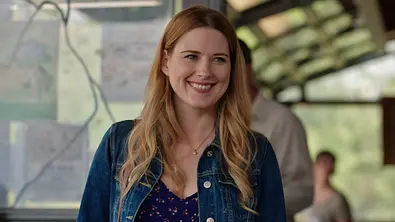 Mel strahlt und schaut zur Seite, der Hintergrund ist unscharf. - Foto: Netflix