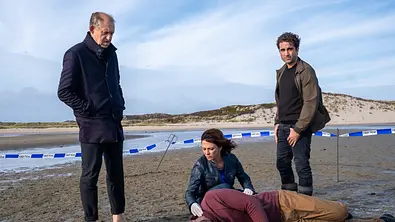Carl Sievers (Peter Heinrich Brix) steht neben Ina Behrendsen (Julia Brendler), die sich gerade zur Leiche von Pablo Hernandez (Iskander Madjitov) herunterkniet, um dessen Puls zu fühlen.  - Foto: ZDF/Manju Sawhney