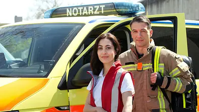 Bei Dr. Nina Haddad und Feuerwehrmann Markus Probst vor einem Notarzt-Wagen. - Foto: ARD/Volker Roloff