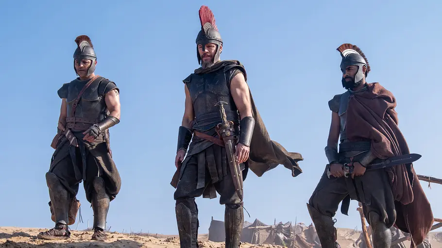 Die Odyssee Jimmy Gonzales, Matt Damon und Himesh Patel stehen in Rüstungen an einem Strand.
