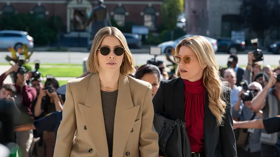 Staffel 1 bietet ein rundes Ende - doch die Geschichte könnte weitergehen. Elizabeth Banks als Nicky und Jessica Biel als Chloe gehen nach vorne. Nicky schaut geschockt zu Chloe, hinter ihnen stehen Reporter:innen mit Kameras.