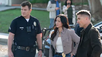 John Nolan in Polizeiuniform, Lucy Chen mit Dienstmarke am Gürtel und Tim Bradford in schwarzer Jacke stehen neben einem Auto. - Foto: TMDB