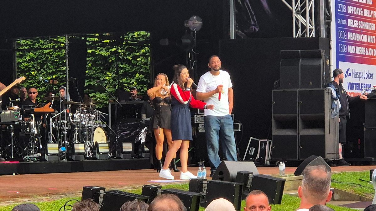 Die wenigen Kinder vor Ort freuten sich vielleicht über die Übersetzerin, doch alle anderen reagierten eher irritiert. Will Smith steht mit einer Übersetzerin auf der Bühne. Sie spricht in ihr Mikrofon, er wartet ab.