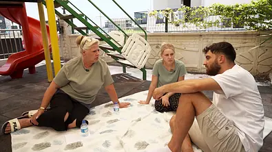 Von links nach rechts: Silvia Wollny sitzt mit Tochter Loredana und Schwiegersohn Servet im Sand eines Spielplatzes. - Foto: RTL2