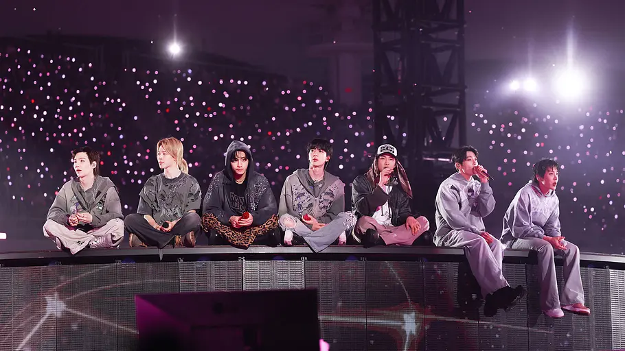 BTS BTS sitzen auf der Bühne und schauen ins Publikum.